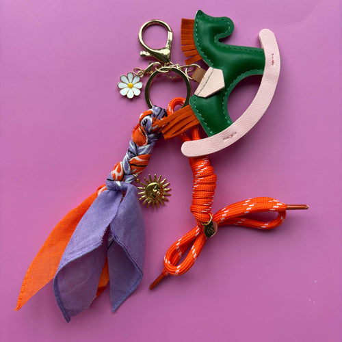 Tasaccessoire bagchain gekleur paars oranje met gouden bedels, bandana en hermes look pony