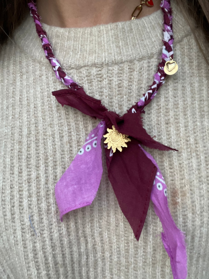 Close up van gevlochten bandana ketting burgondy en lila met gouden bedels 