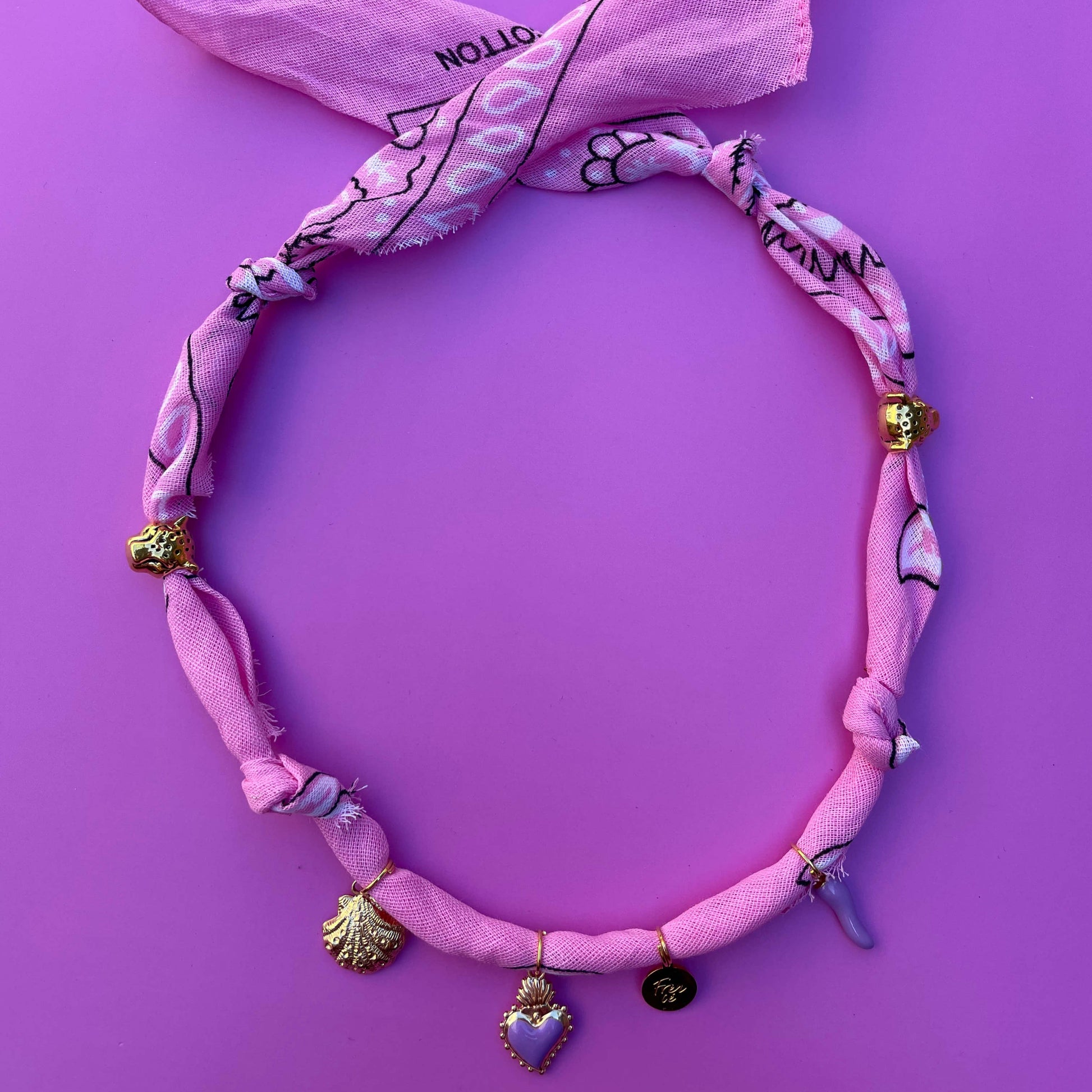 Handgemaakte roze bandana ketting, geknoopt van katoen, met gouden en paarse bedels – trendy accessoire voor elke look.