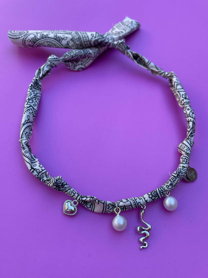 Geknoopte wit-zwarte bandana ketting met zilveren bedels, ideaal voor een bohemian festivalstijl of casual zomerse outfits.
