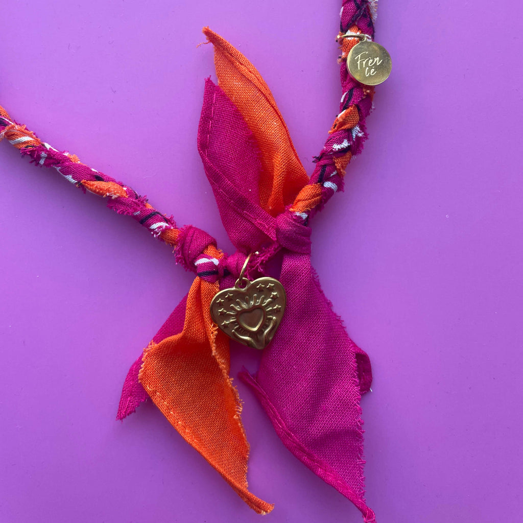 Close-up van de fuchsia-oranje bandana ketting met gouden hartvormige bedel van 100% katoen – uniek handgemaakt accessoire.