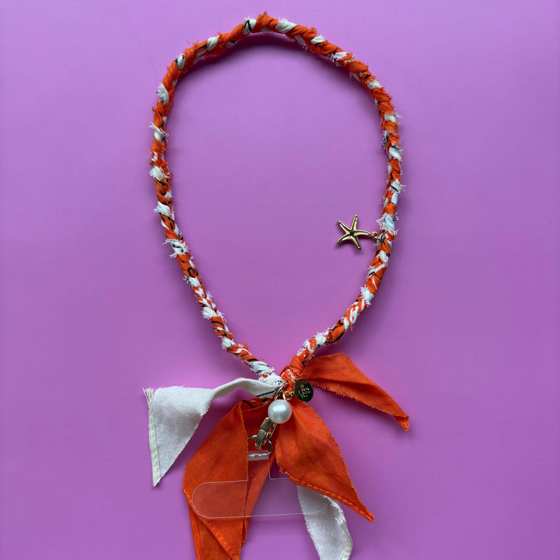 Gevlochten telefoonkoordje bandana oranje & beige met gouden bedels en bevestiging.