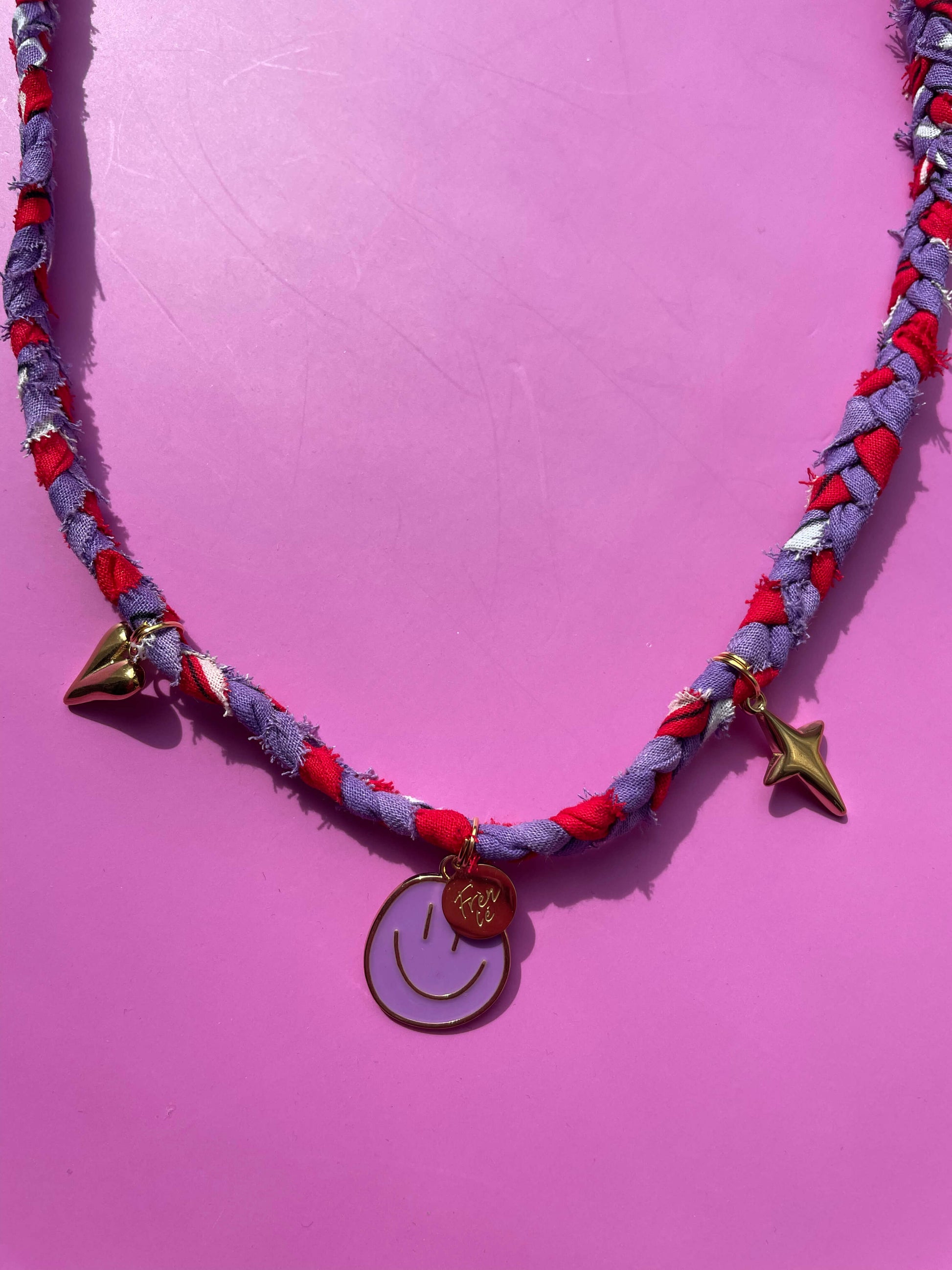 Detail van de gevlochten bandana ketting met meerdere gouden bedels